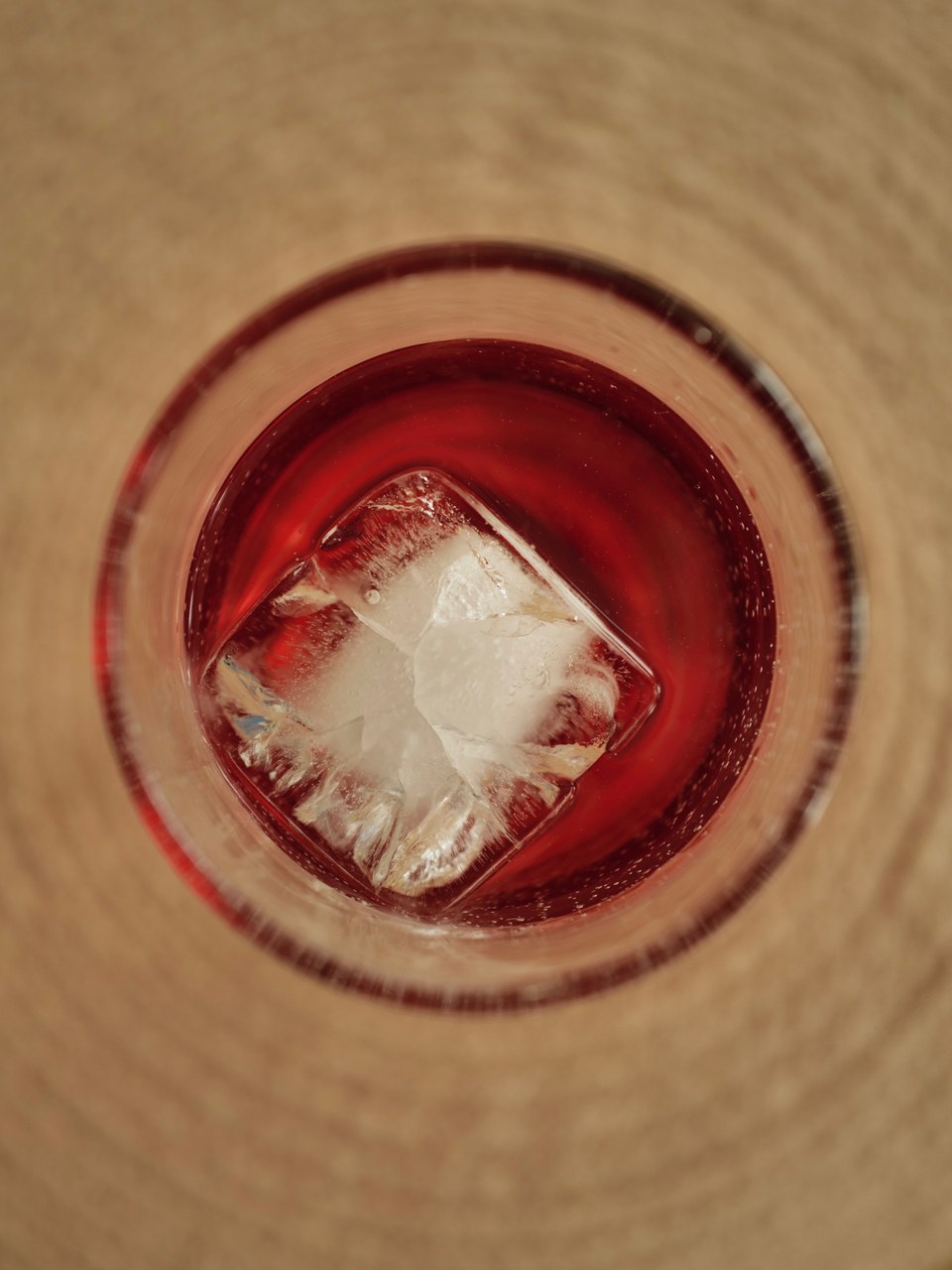 Looking down into a red drink with a single ice cube