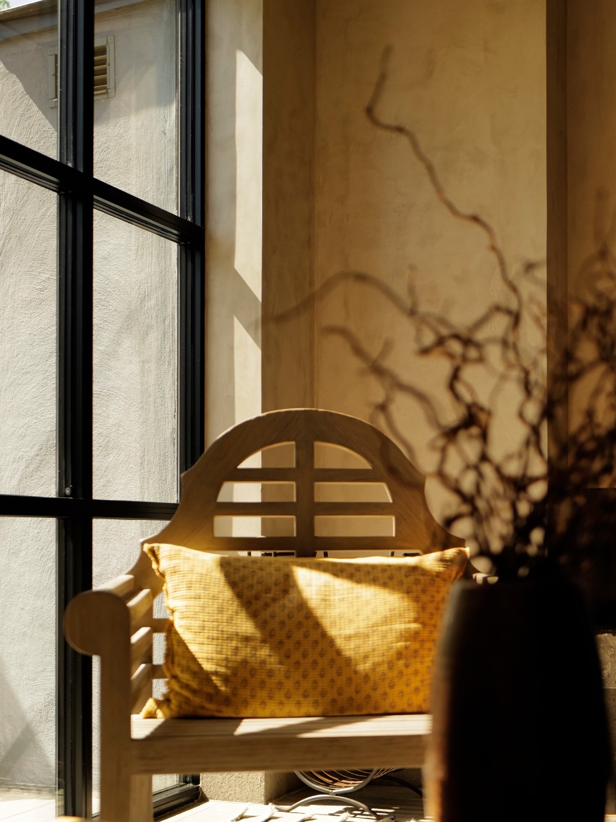 Sunlit interior with a wooden chair, yellow cushion, and dried branches