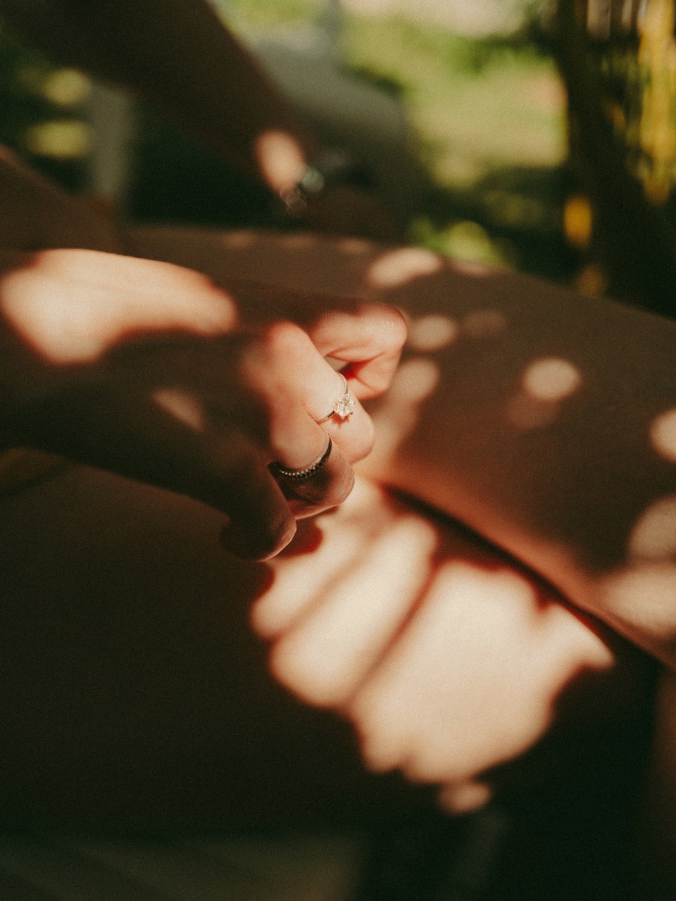 Hand with a diamond ring in dappled afternoon sunlight